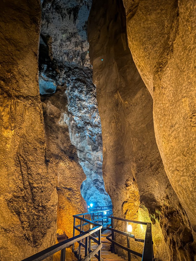 Illuminated wooden walkway winding between narrow limestone walls inside Diamond Cave.