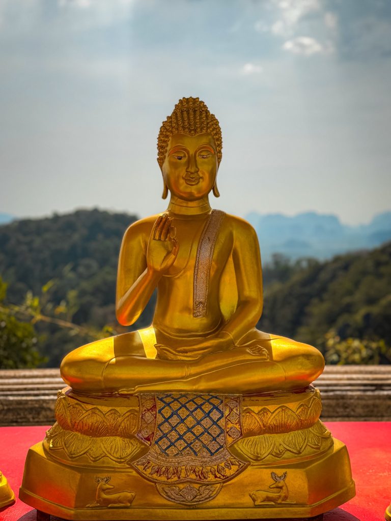 Golden Buddha statue overlooking the mountains from the Tiger Cave Temple summit