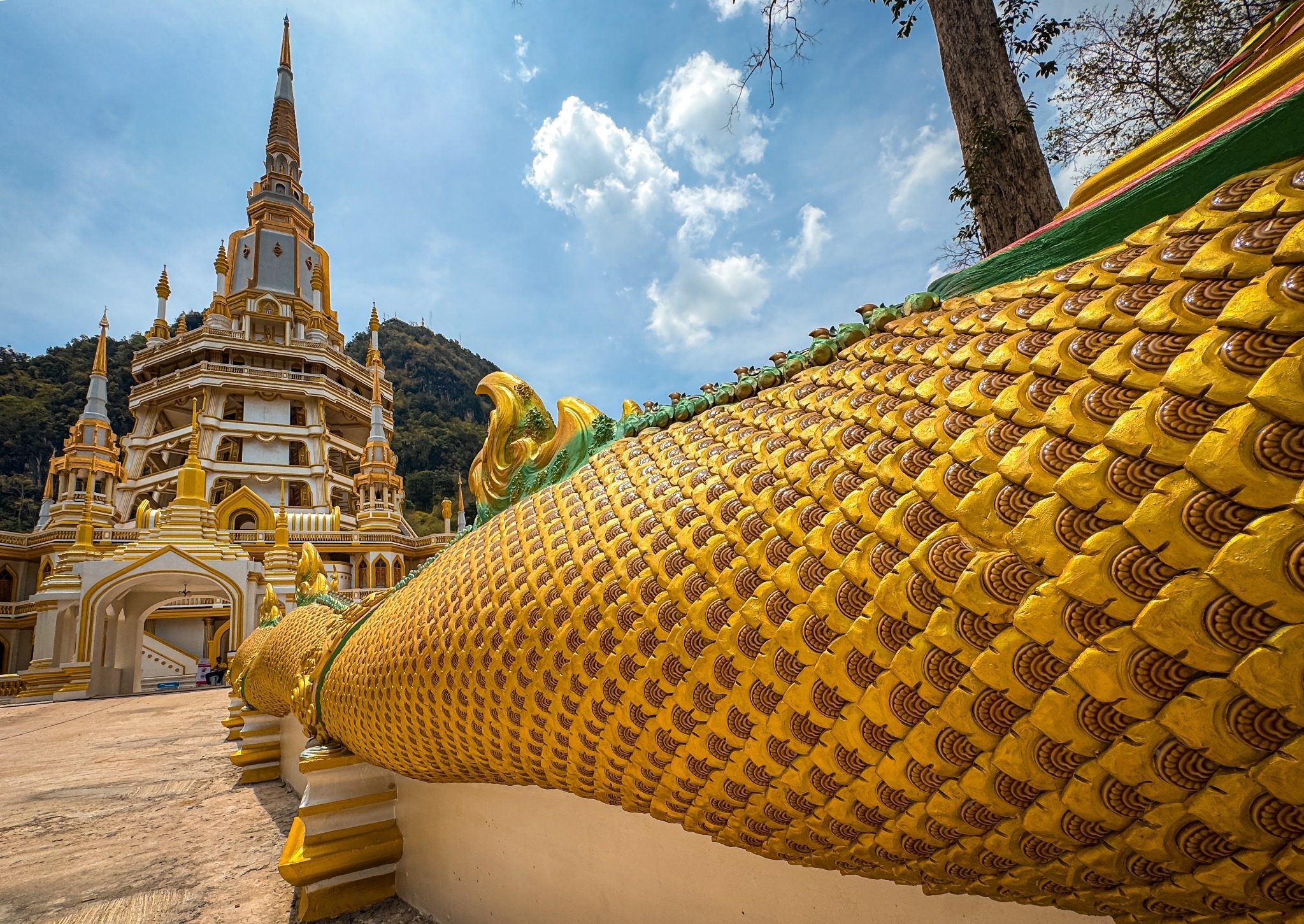 Detailed golden naga railing leading toward the Tiger Cave Temple pagoda
