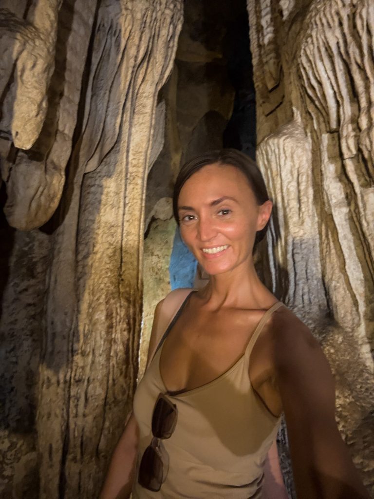 Woman taking a selfie among tall limestone formations inside Diamond Cave in Railay.