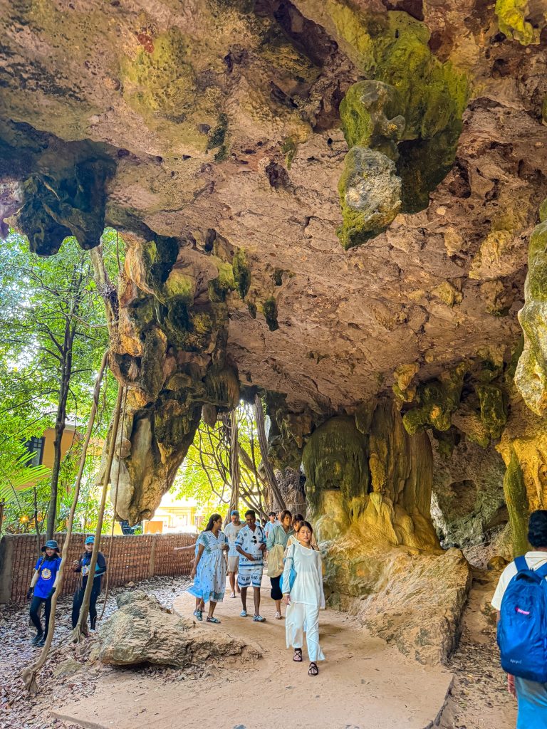 Visitors walking beneath limestone overhangs along the path to Phra Nang Beach in Railay.