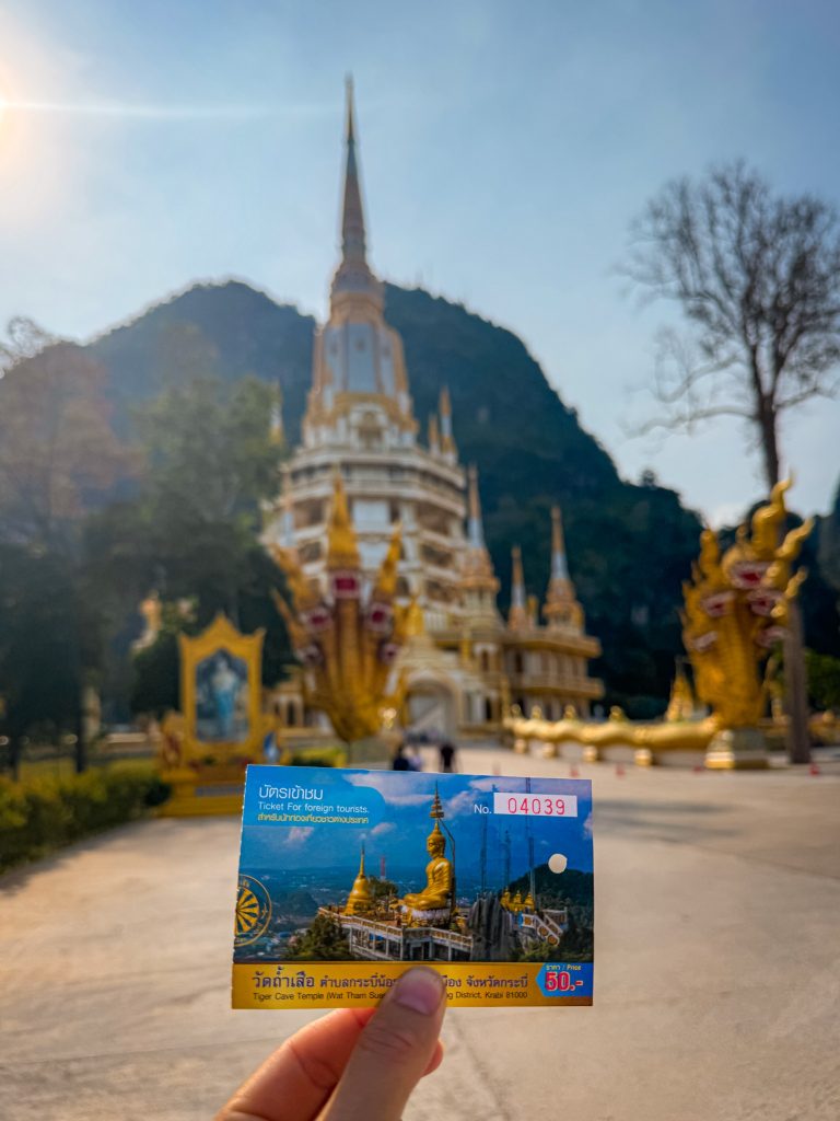 Tiger Cave Temple entry ticket held in front of the main pagoda in Krabi