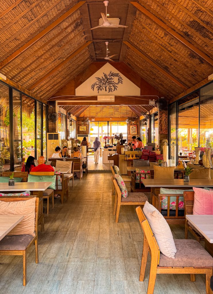 Open-air restaurant dining room with wooden furniture and a thatched ceiling at Villa Cha-Cha Krabi.