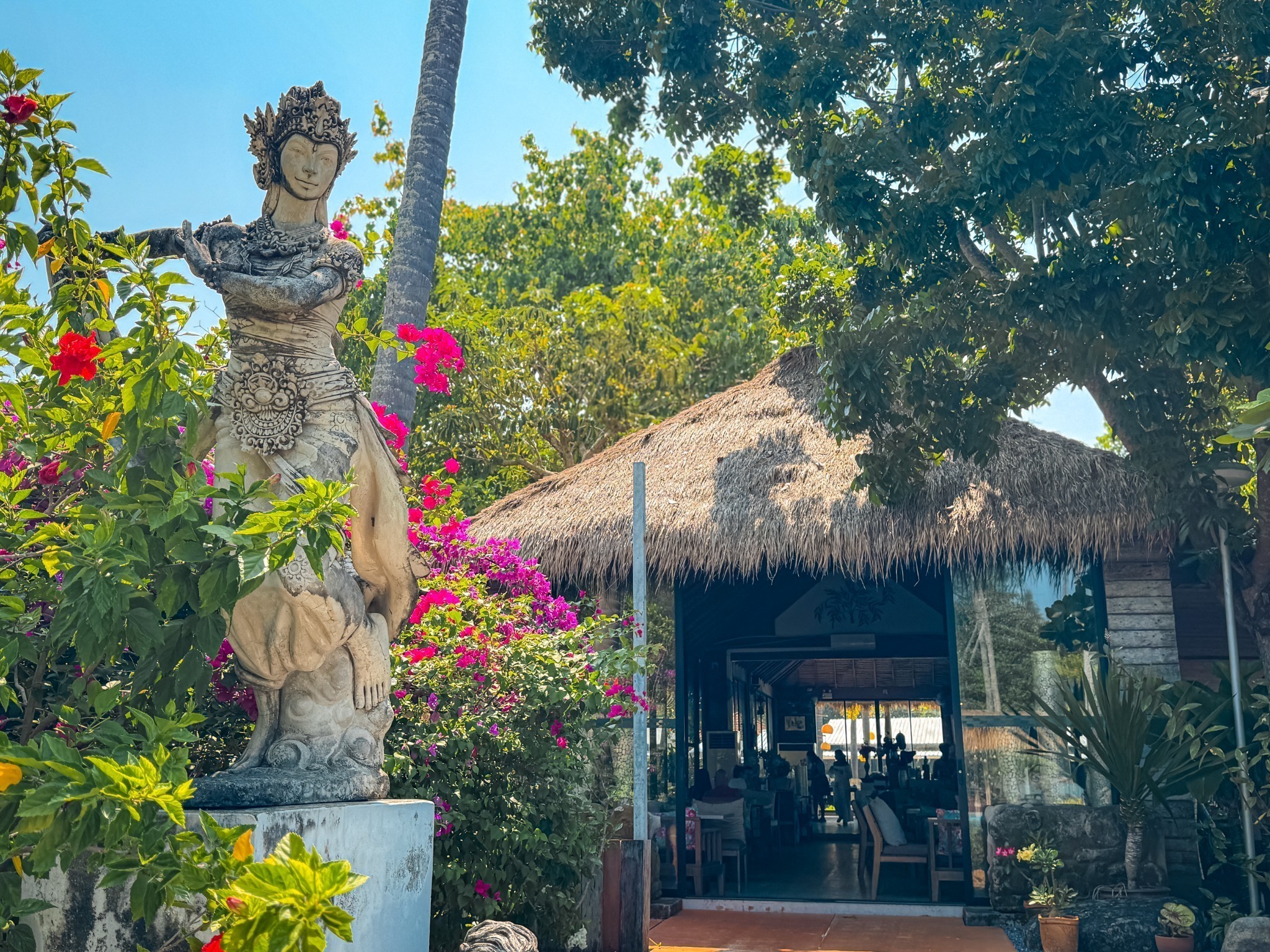 Thai statue and bougainvillea beside the open-air restaurant entrance at Villa Cha-Cha Krabi.