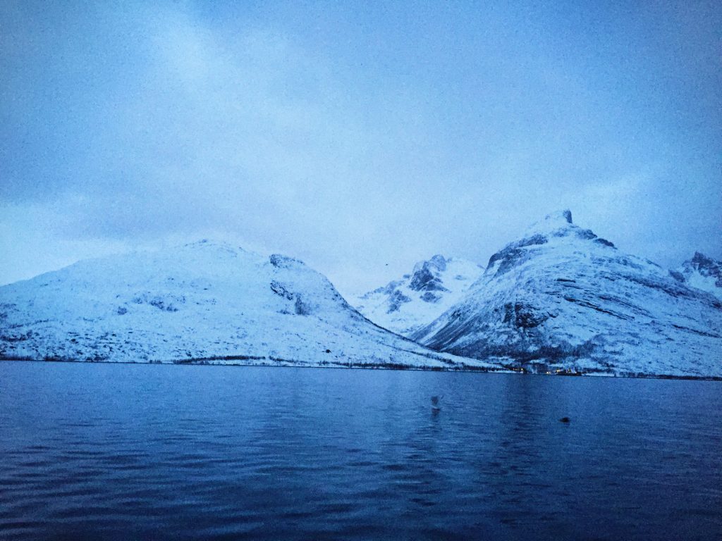 Snow covered mountains behind the water at twighlight in Tromso, Norway