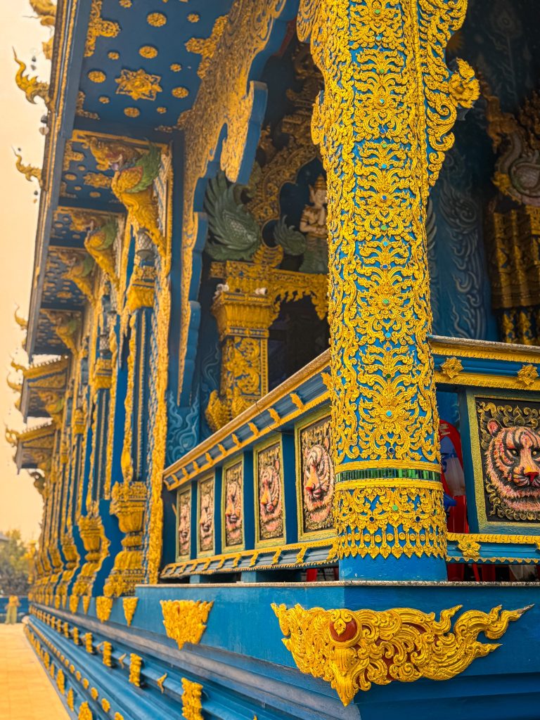 Close-up of blue and gold columns and painted tiger panels along the Blue Temple exterior.