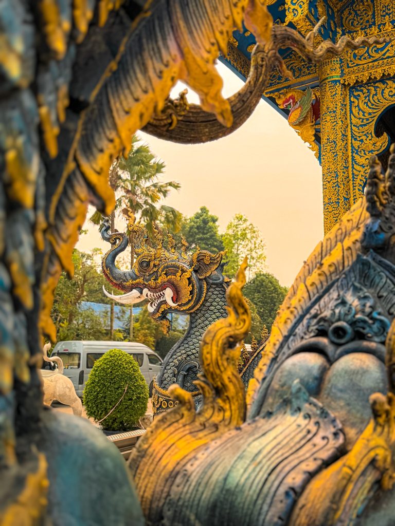Close-up view through blue and gold naga sculptures at the Blue Temple in Chiang Rai.