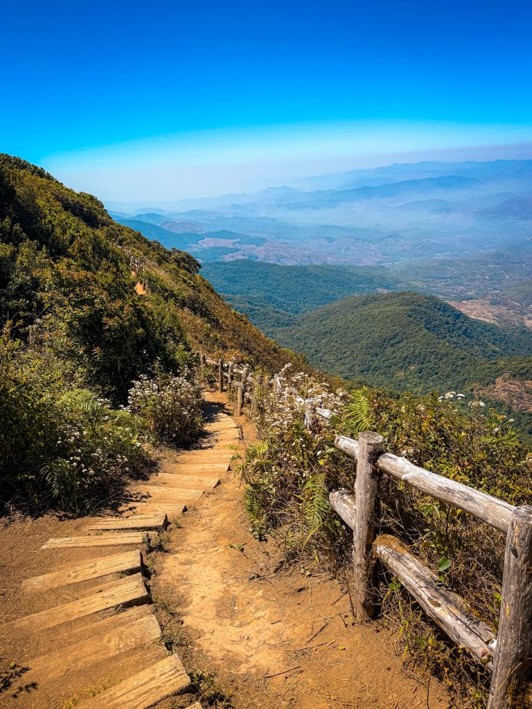 Mountain hiking trail descending along the Kew Mae Pan Nature Trail with expansive views across Doi Inthanon.