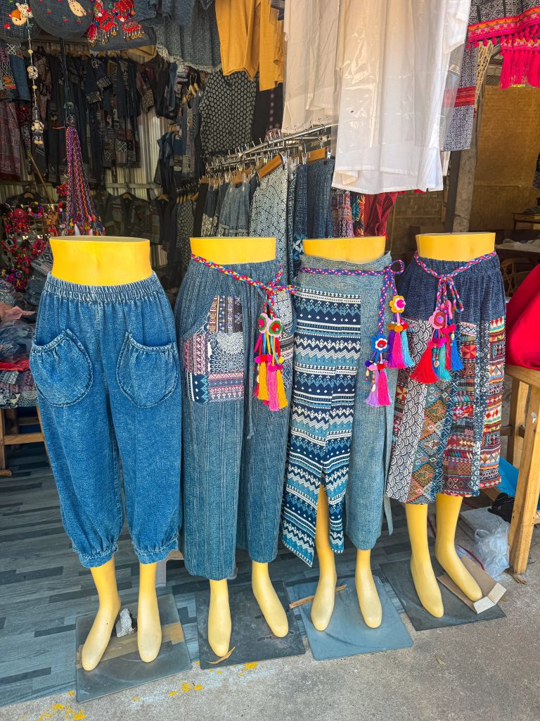 Traditional patterned clothing and colorful textiles displayed for sale at a Hmong market near Doi Inthanon National Park.