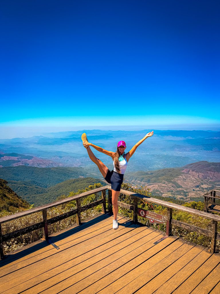 Traveler doing a standing y-scalesplit at a mountain viewpoint while trekking the Kew Mae Pan Nature Trail in Doi Inthanon.