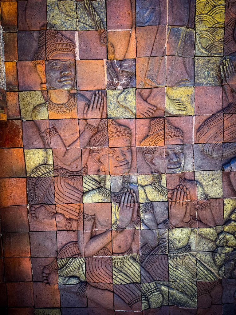 Detailed carved Buddhist figures and decorative tiles on a mural at the Royal Twin Pagodas in Doi Inthanon.