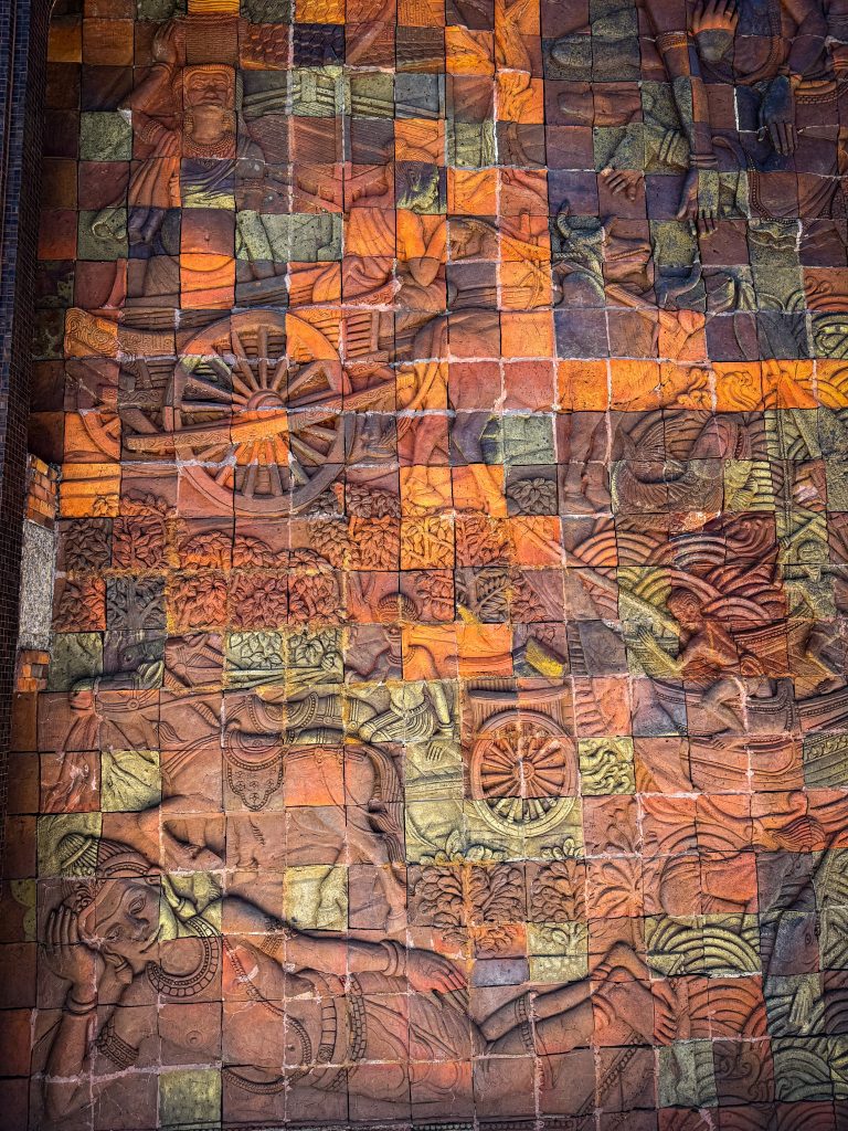 Intricate historical and Buddhist scenes carved into colorful tiles at the Royal Twin Pagodas in Doi Inthanon.