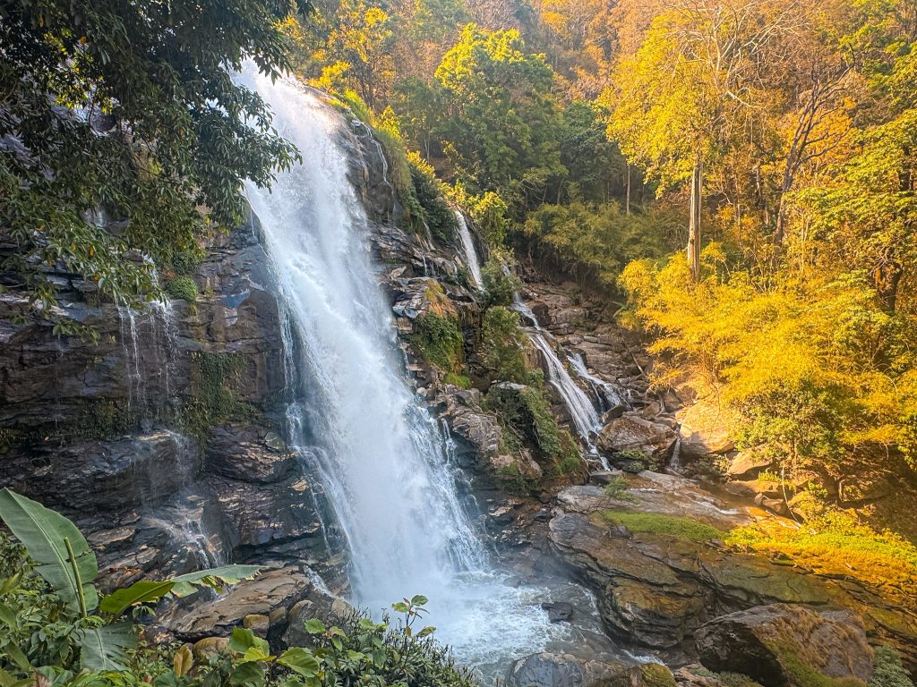 Powerful Wachirathan Waterfall cascading over a rocky cliff surrounded by forest in Doi Inthanon National Park.