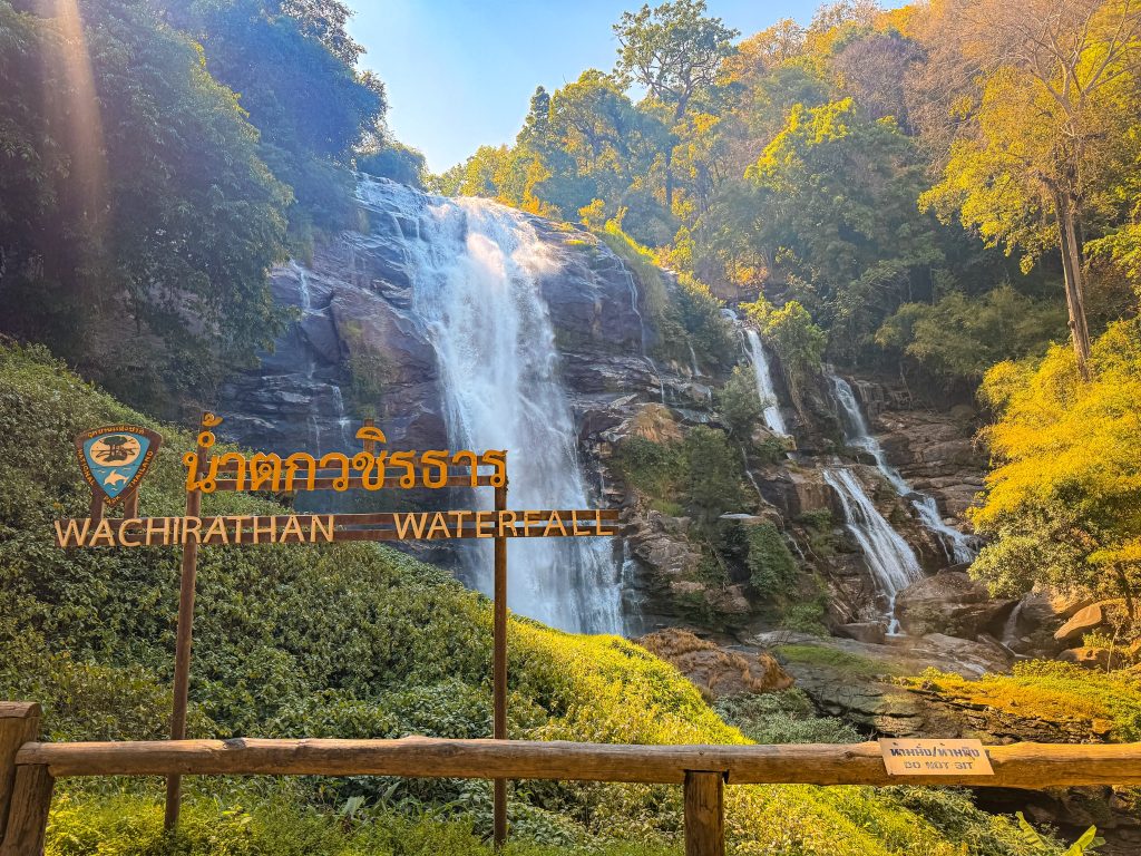 Wachirathan Waterfall sign in front of the large cascading waterfall at Doi Inthanon National Park in Thailand.