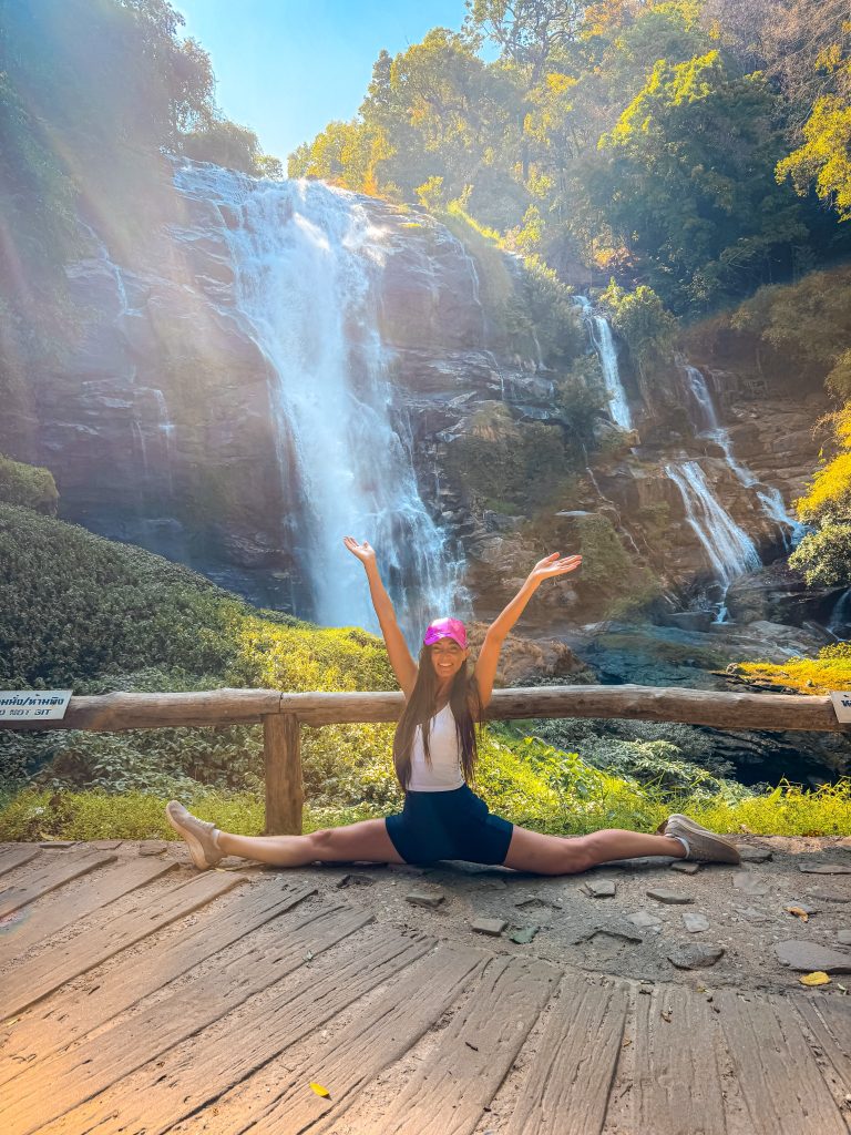 Traveler doing a split in front of Wachirathan Waterfall during a Doi Inthanon National Park tour from Chiang Mai.