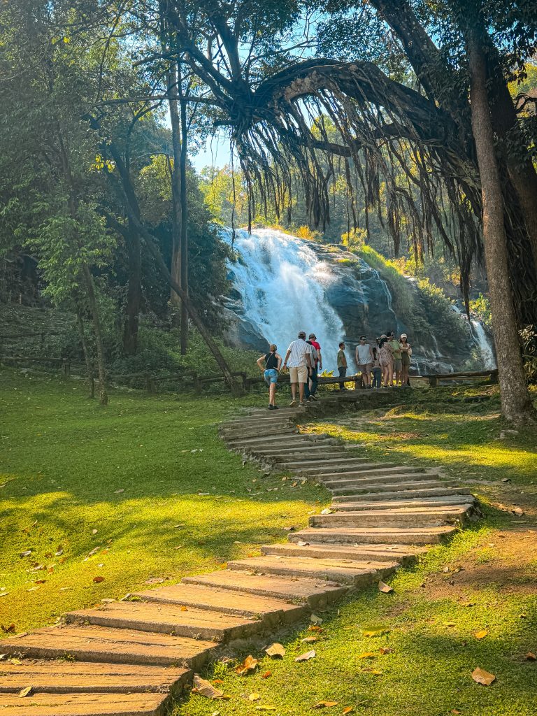 Walking path and steps leading toward Wachirathan Waterfall surrounded by lush forest in Doi Inthanon National Park.