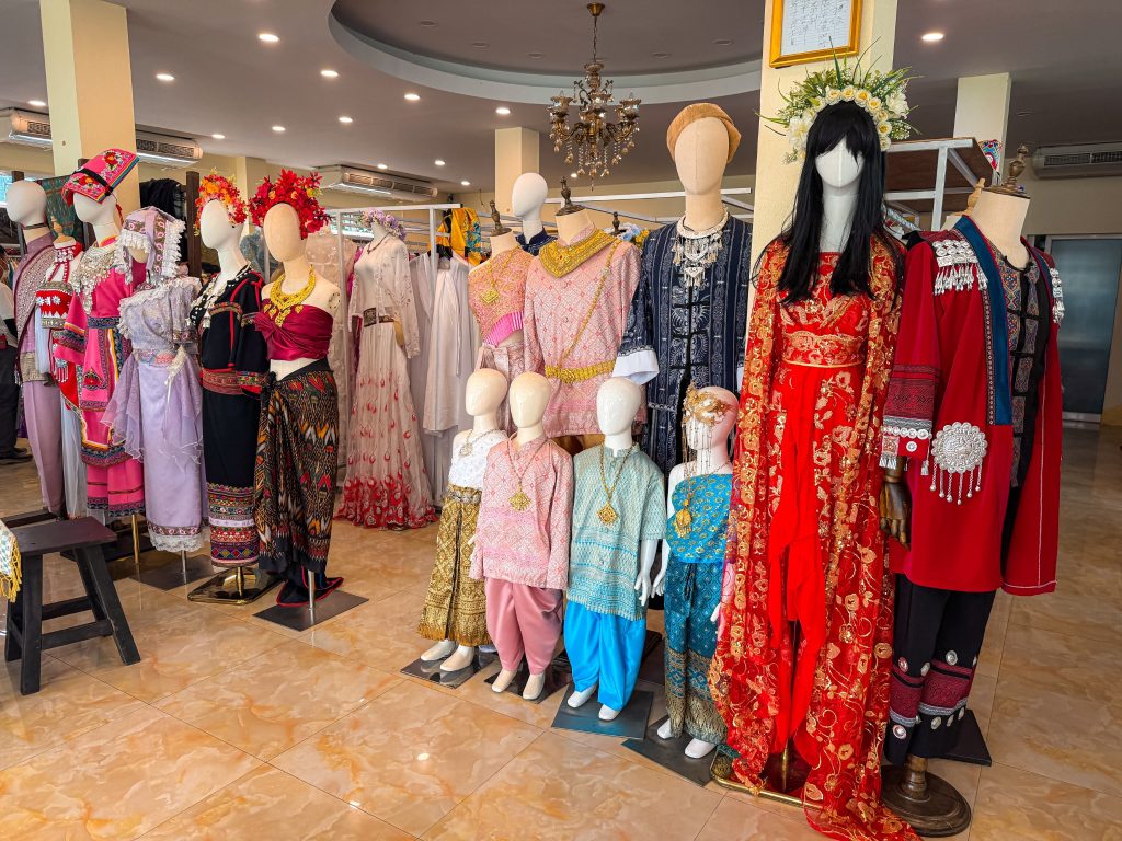 Mannequins displaying colorful traditional Thai clothing inside a dress rental shop in Chiang Rai.